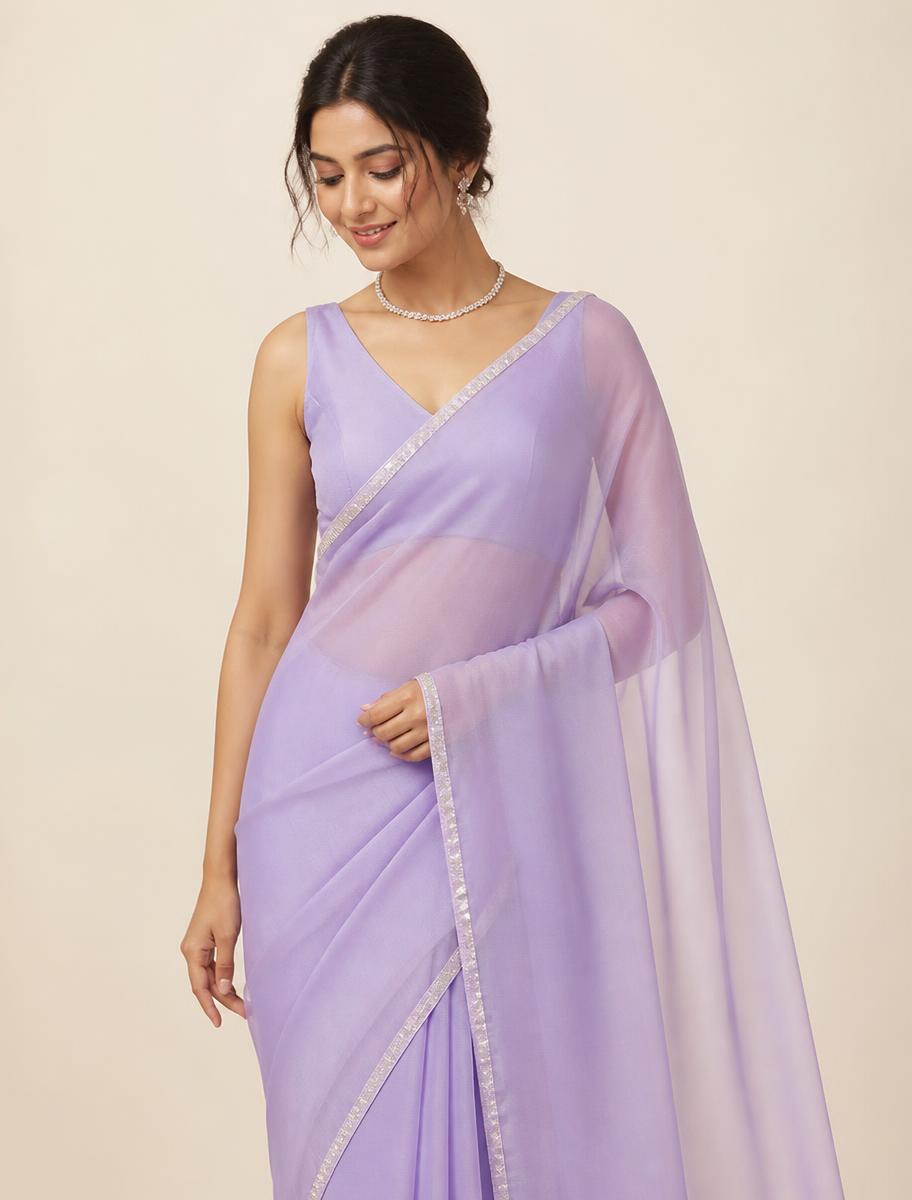 Woman wearing a lavender chiffon saree with a silver border