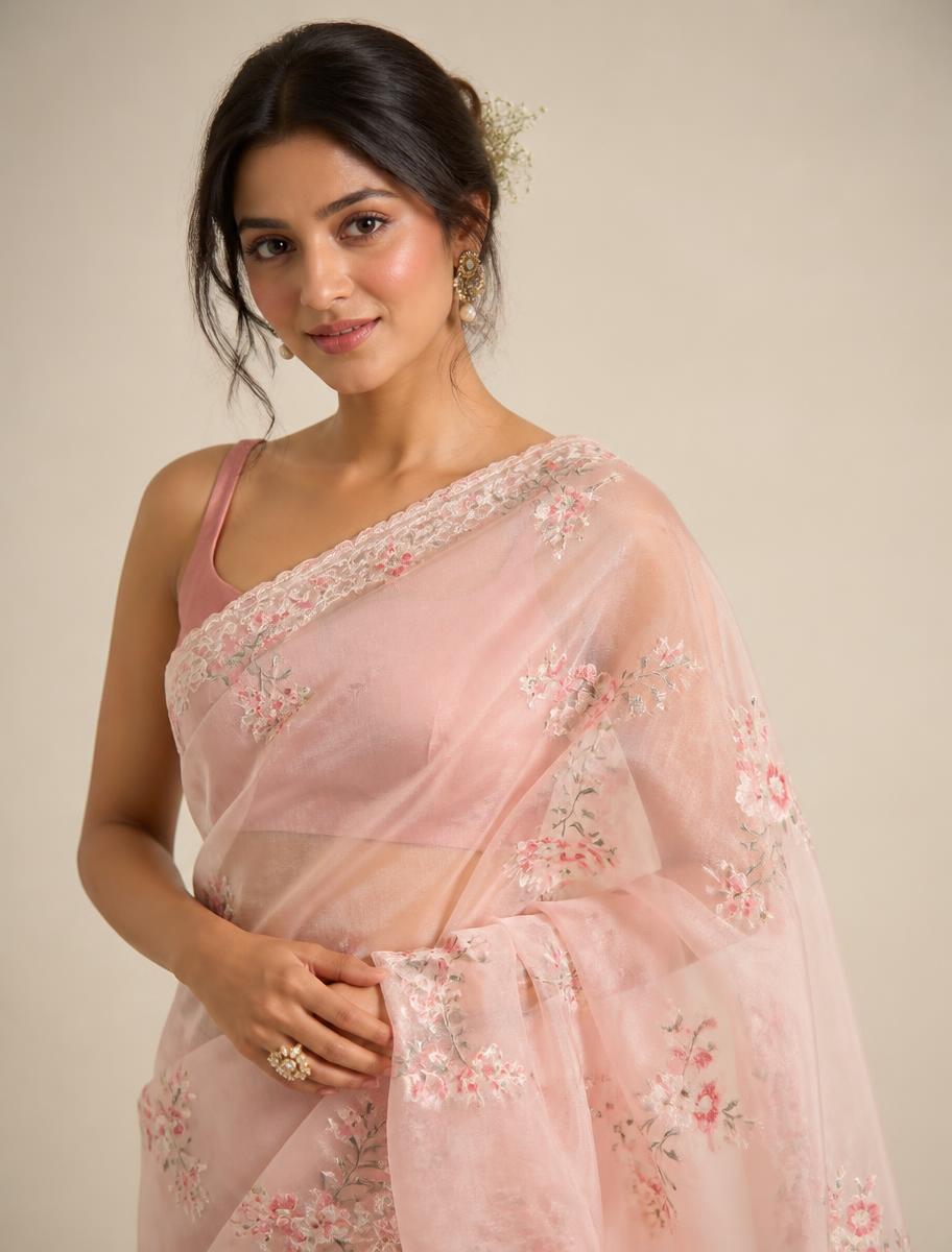 Woman wearing a blush pink organza saree with floral embroidery
